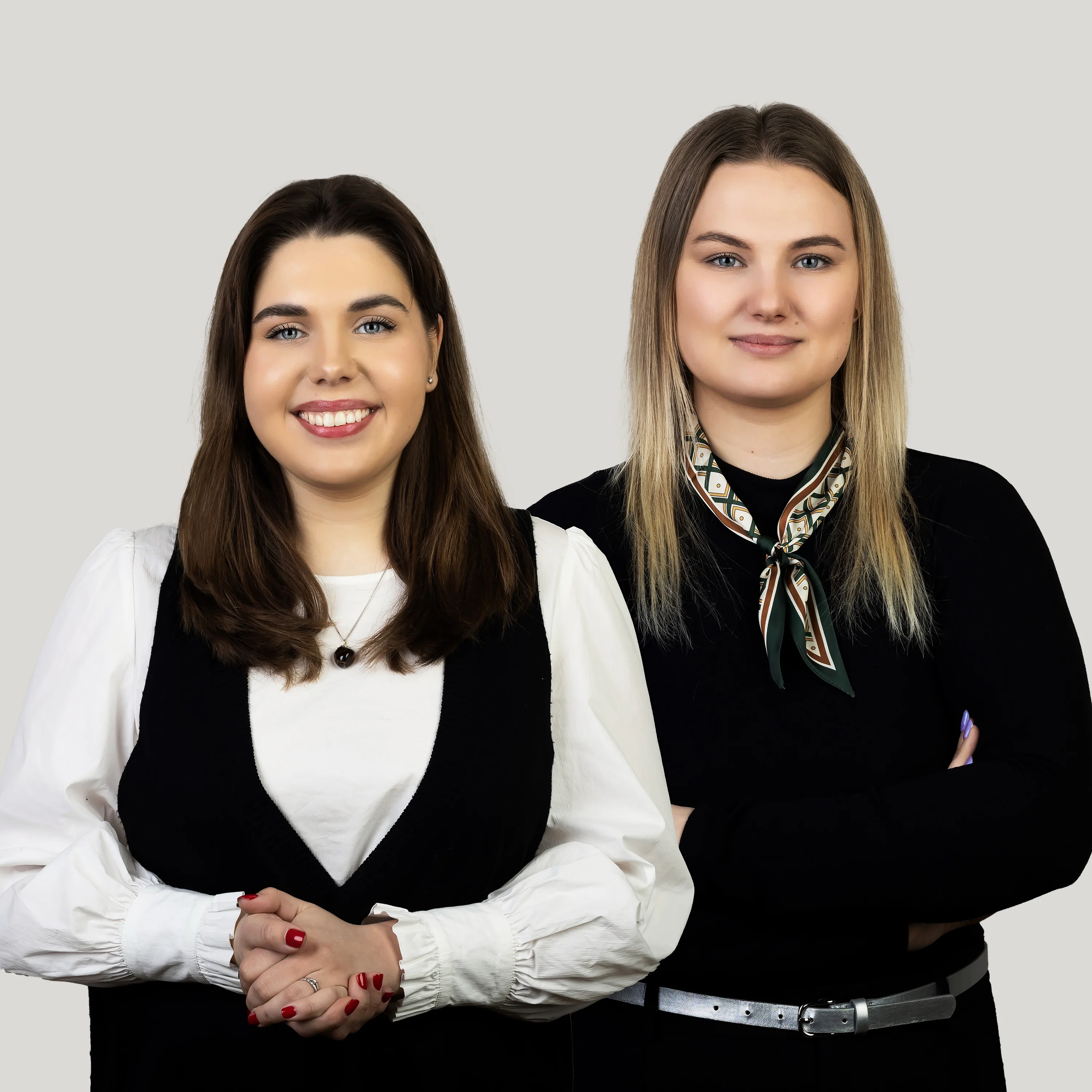 Two female study info specialists wearing black and white outfits with one on the left in a white blouse under a black vest and one on the right in a black top with a patterned scarf willing that you can contact to answer your questions about studies at KTU.