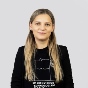 A young blonde woman with long straight hair, wearing a black sweater, smiling professionally against a neutral background.