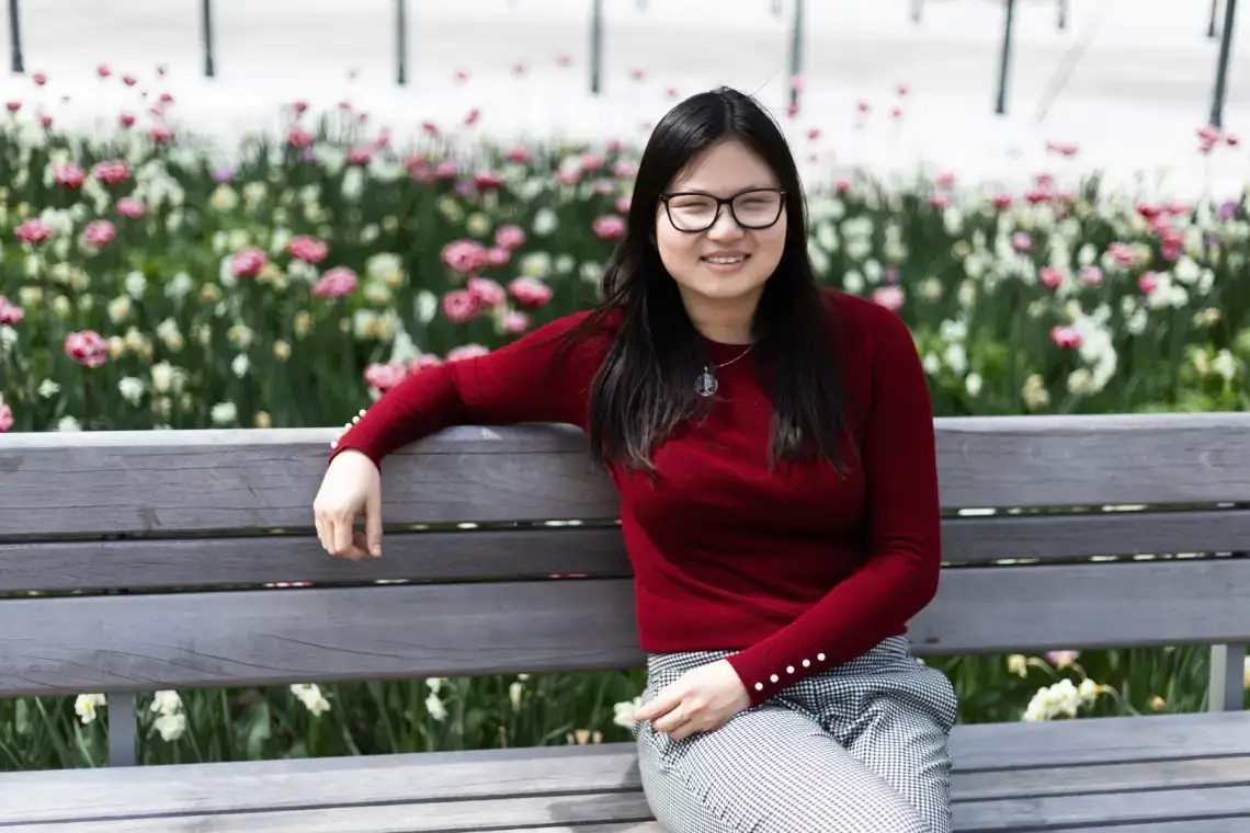 Nieves Ganghe Pedros Chamorro, a student from Spain, is sitting on a bench enjoying city greenery.