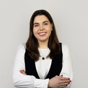 Smiling woman dressed in white on grey background